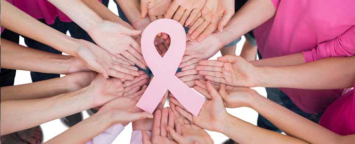 women in a circle holding a breast cancer sign