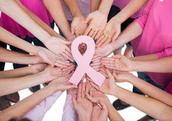 women in a circle holding a breast cancer sign